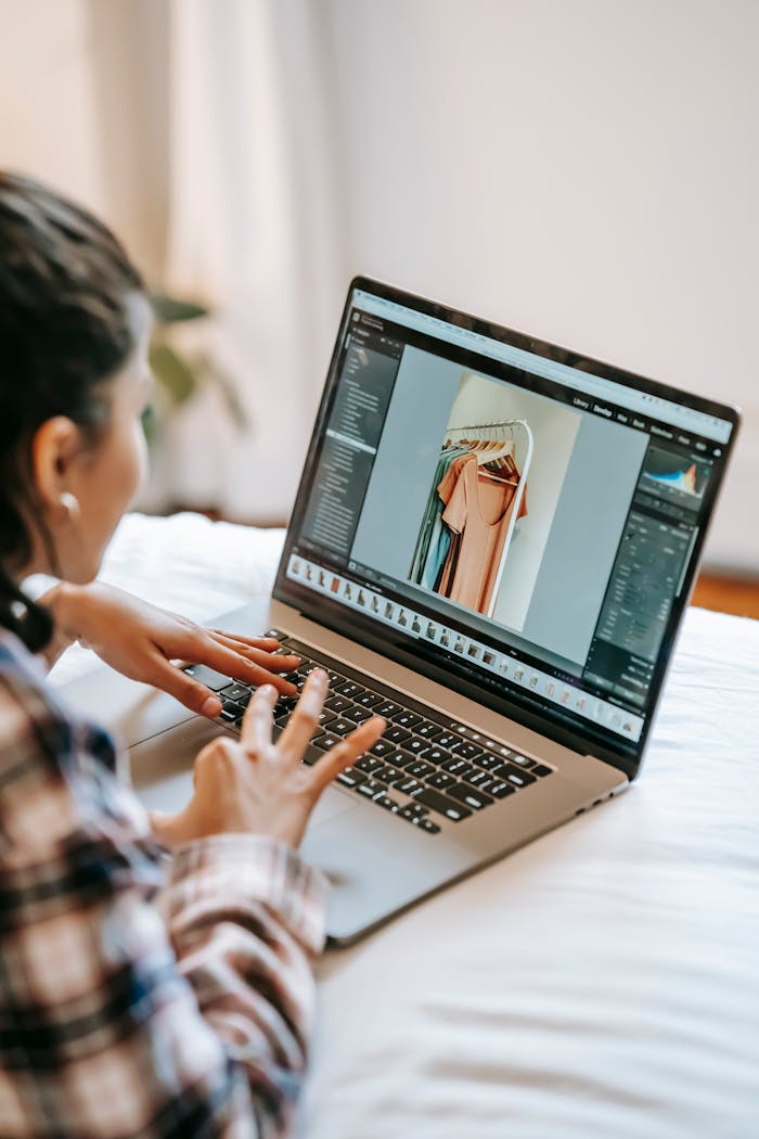 A woman editing fashion photos at home on a laptop, focused and creative.